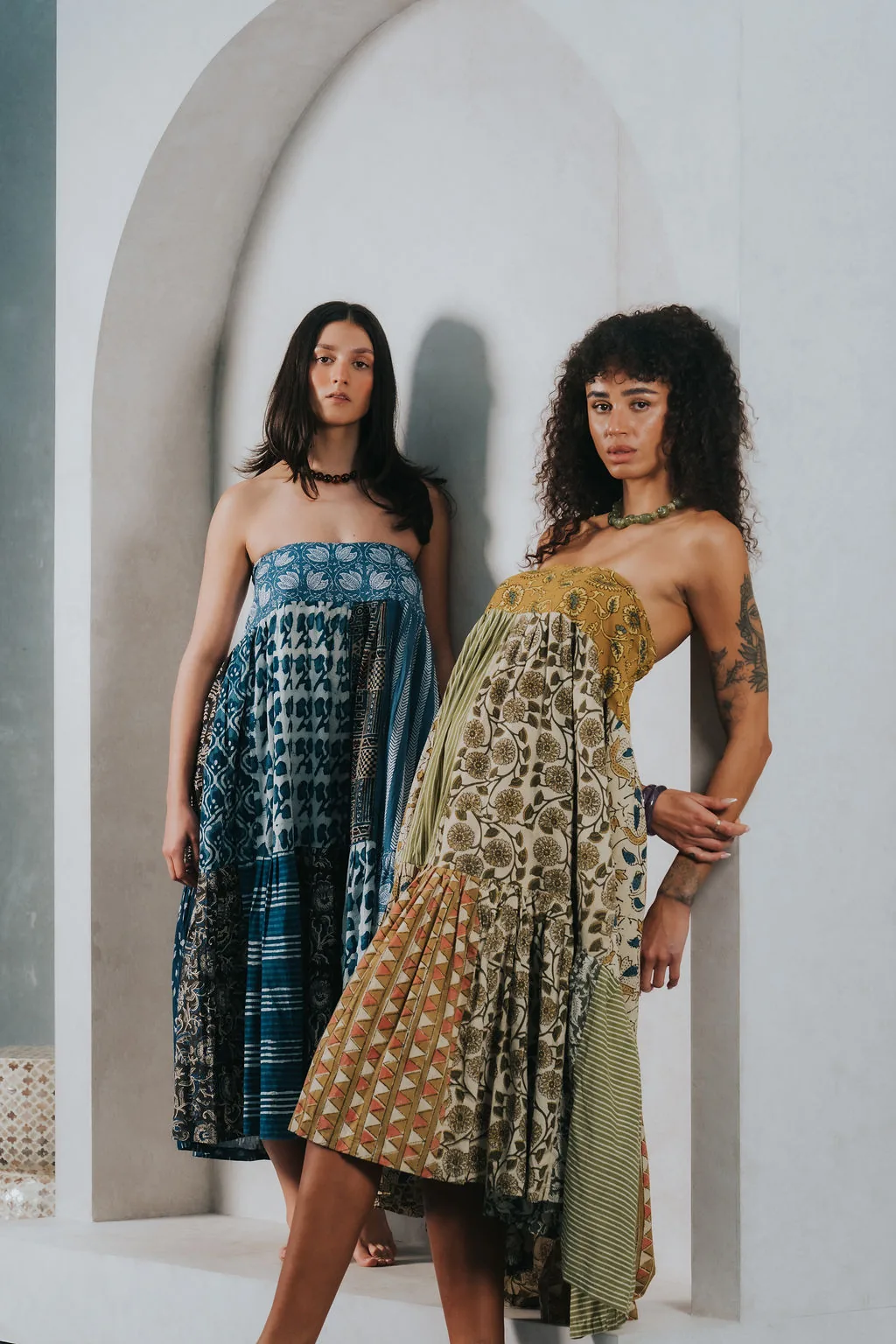 Two models wearing RILA Design hand block printed dresses in an arched alcove